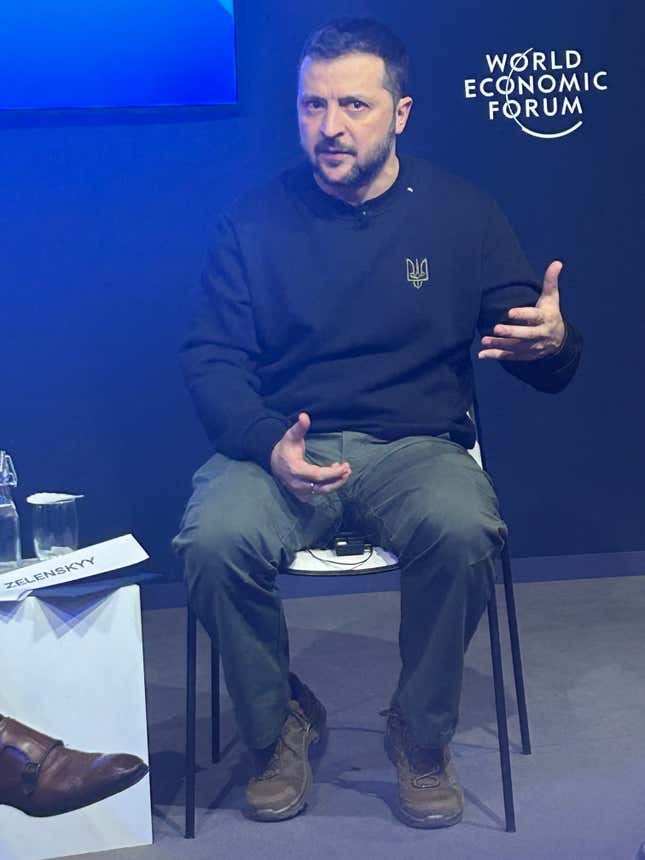 Volodymyr Zelensky sits in a chair and speaks at a press event