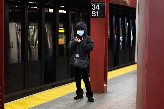 NEW YORK, NY - MARCH 16: A woman wears a protective mask while on her phone at 34th Street subway station. 