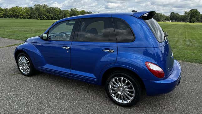 A rear 3/4 shot of the electric blue PT cruiser parked in front of a grassy lot