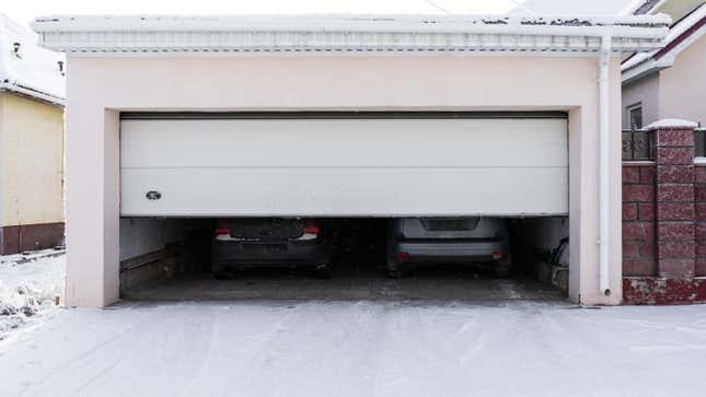 Exterior of a garage attached to a house. garage with two cars inside in winter. semi-open sectional doors.