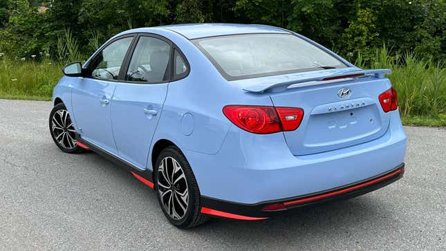 A rear 3/4 shot of the performance blue 2008 Elantra parked in front of bushes