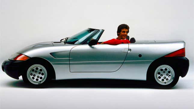 A photo of a man in a red jumper sat in a Ford concept car. 