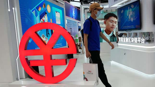 A visitor passes by a logo for the e-CNY, a digital version of the Chinese Yuan, displayed during a trade fair in Beijing, China.