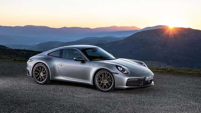 A silver 911 parked in front of a beautiful sunset vista