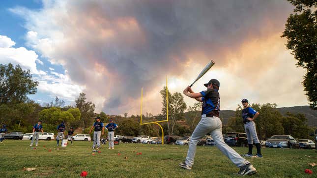 Little League players warm up before a game as the Valley Fire burns in the background near San Diego.