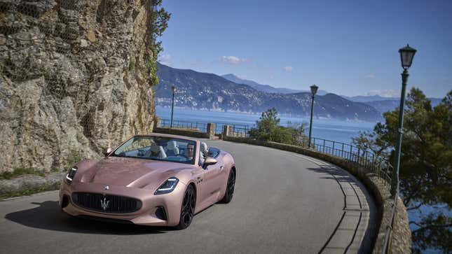 A photo of a pink Maserati GranCabrio EV driving on a road. 