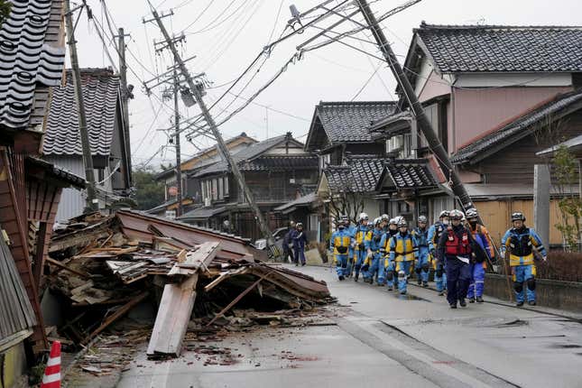 Police walk past collapsed houses hit by earthquakes in Suzu, Ishikawa prefecture, Japan Wednesday, Jan. 3, 2024. Rescue workers and canine units urgently sifted through rubble Wednesday ahead of predicted freezing cold and heavy rain in what the prime minister called a race against time after powerful earthquakes in western Japan killed multiple people. Dozens are believed trapped under collapsed buildings.(Kyodo News via AP)