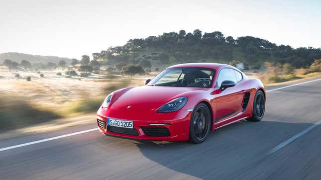 A red Porsche 718 Cayman T driving in front of a hill