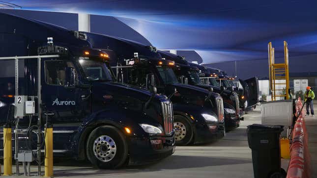 A photo of a fleet of self-driving trucks in a tent. 