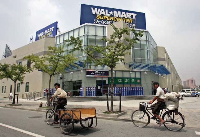 Los trabajadores pasan en triciclo frente a la primera tienda Wal-Mart en Shanghái el 25 de julio de 2005. 