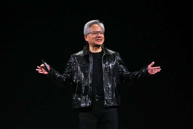 Jensen Huang wearing a shiny black crocodile leather jacket over a black shirt and pants speaking with both of his hands up