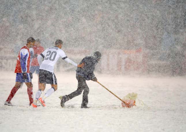 US defender Geoff Cameron helps a groundskeeper shovel the pitch.