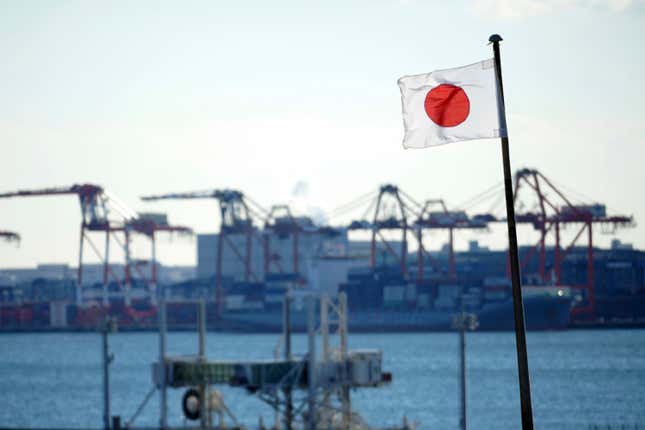 FILE - A national flag flies near a container port Thursday, Jan. 20, 2022, in Tokyo. Japan&#39;s exports fell slightly in November, 2023, from a year earlier, the first decline in three months, while imports were down nearly 12%. (AP Photo/Eugene Hoshiko, File)