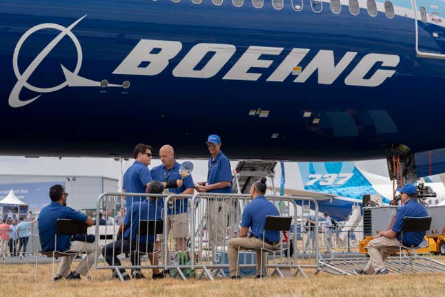 Boeing workers beneath a Boeing 777X at the Farnborough Airshow in Farnborough, England. 