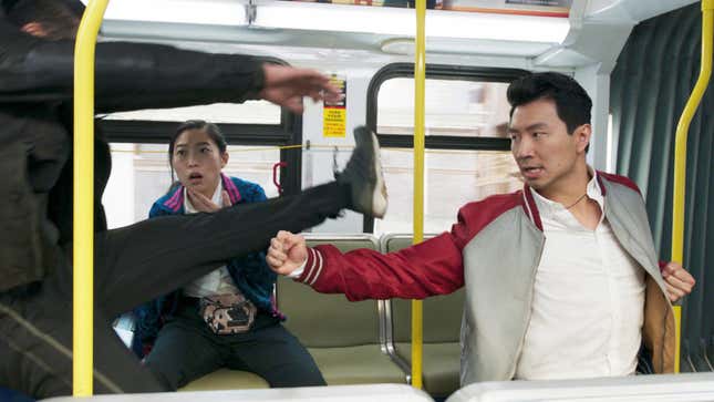 Simu Liu's Shang-Chi punches a goon on a city bus while Awkwafina's Katy gasps in shock.