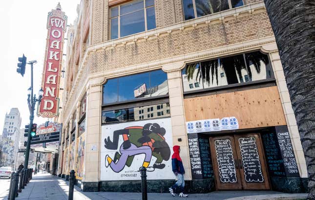 “A person walks by a boarded-up shop in Oakland, California on February 12, 2021. - Racial minorities have borne the brunt of the Covid-19 pandemic in the United States, with higher rates of death, unemployment and business failure, and less success obtaining federal government assistance intended to provide relief.”