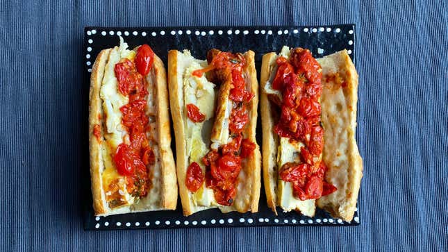 Three Potato & Egg Sandwiches on black plate, topped with tomatoes