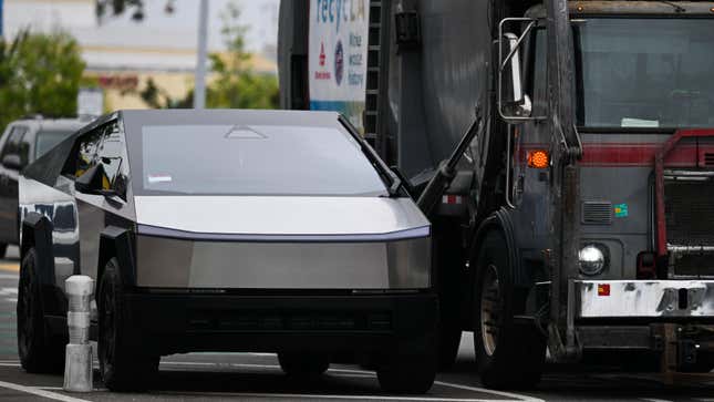 A Tesla Cybertruck electric vehicle sits parked next to a garbage truck in Los Angeles, California, on May 15, 2024. 