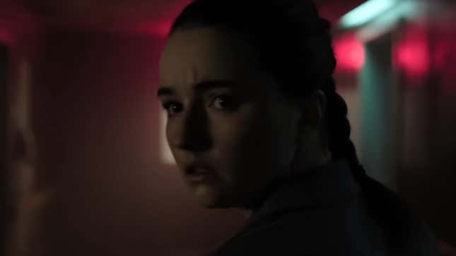 Abby looks down a dark hallway with a concerned expression.