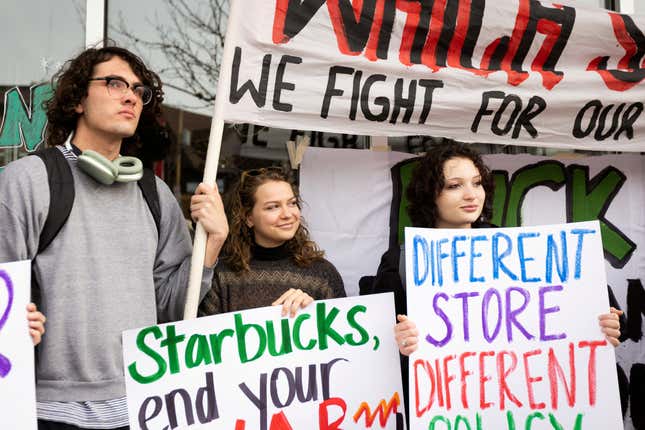 Three workers hold colorful signs while striking outdoors.