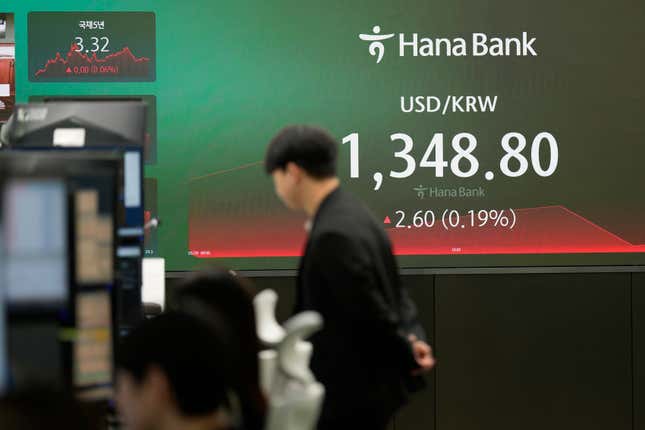 A currency trader watches computer monitors near the screen showing the foreign exchange rate between U.S. dollar and South Korean won at a foreign exchange dealing room in Seoul, South Korea, Friday, March 29, 2024. Asian shares were mostly higher Friday in quiet holiday trading, with markets closed in Hong Kong, Sydney, Singapore and India, among other places. (AP Photo/Lee Jin-man)