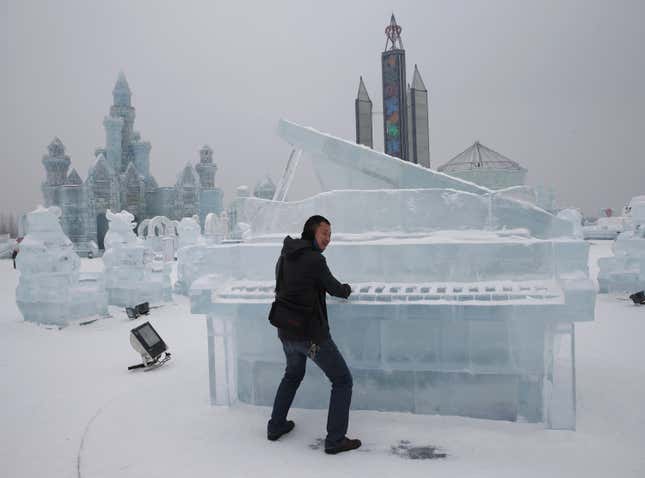 A visitor has his picture taken with a piano-shaped ice sculpture ahead of the 31st Harbin International Ice and Snow Festival in the northern city of Harbin, Heilongjiang province, January 4, 2015. The winter festival will be officially opened on January 5, 2015. REUTERS/Kim Kyung-Hoon