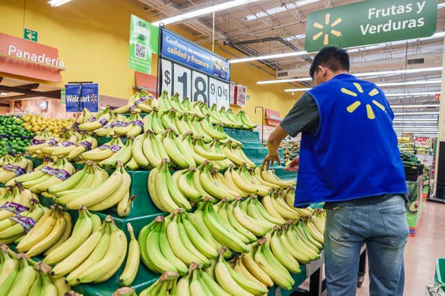 A Walmart employee restocking bananas. 