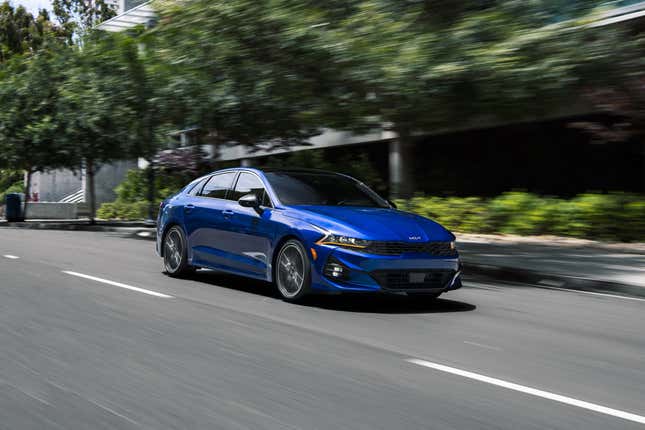 A blue sedan warps the fabric of space and time on a business park road.