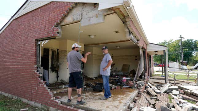 Brian Mitchell, right, looks through the damaged home of his mother-in-law along with family friend Chris Hoover, left, Sunday, Aug. 22, 2021, in Waverly, Tenn.