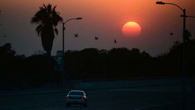 A photo of a car driving off into the California sunset. 