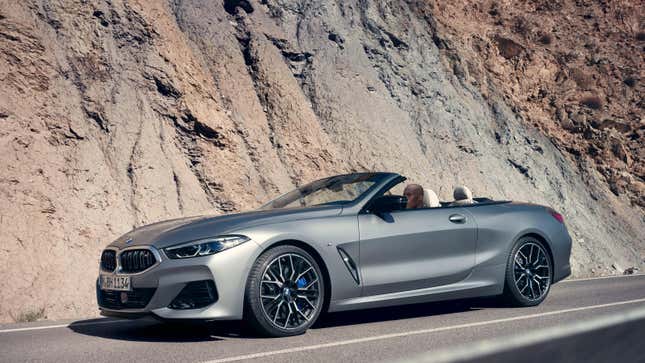 A silver BMW 8 series convertible parked on a cliffside