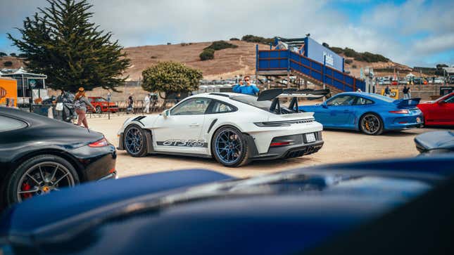 A white on blue 992 Porsche GT3 RS is parked in the Rennsport Reunion parking lot