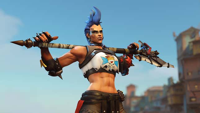 Junker Queen is shown standing with her axe resting on her shoulders in front of a town and blue sky.