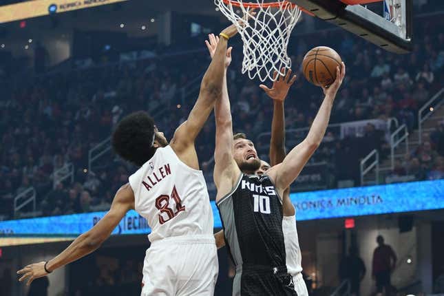 Dec 9, 2022; Cleveland, Ohio, USA; Sacramento Kings forward Domantas Sabonis (10) drives to the basket against Cleveland Cavaliers center Jarrett Allen (31) and forward Evan Mobley (4) during the first half at Rocket Mortgage FieldHouse.