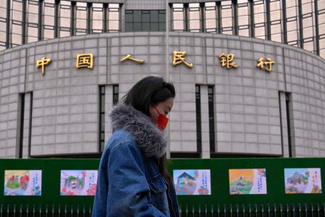 A woman walks by China&#39;s central bank, or the People&#39;s Bank of China in Beijing, Tuesday, Feb. 20, 2024. China&#39;s central bank announced it cut its five-year loan prime rate while leaving its one-year rate unchanged. (AP Photo/Andy Wong)