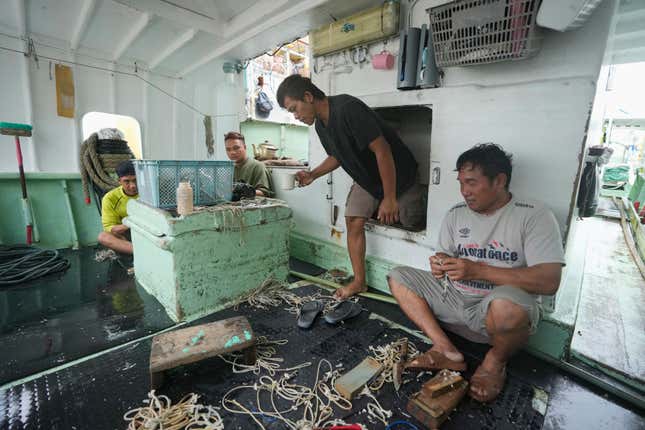 FILE - Foreign helpers do some maintenance work on their fishing tools while sitting on their boat docked at the Tomari fishery port in Naha in the main Okinawa island, southern Japan, on June 1, 2023. The Japanese government on Friday, Feb. 9, 2024, adopted plans to scrap its current foreign trainee program, criticized as a cover for importing cheap labor, and replace it with a new system that it says will actually teach skills and safeguard their rights as Japan desperately seeks to attract more foreign workers to supplement its aging and shrinking workforce. (AP Photo/Hiro Komae, File)