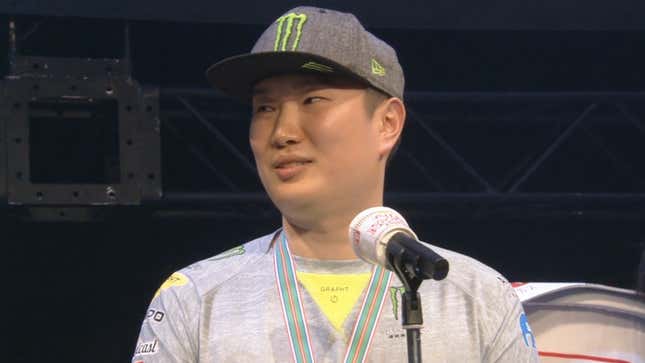 Seon-woo "Infiltration" Lee stands in front of a microphone and glances at something off-screen.