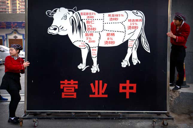 FILE - Restaurant workers move a sign advertising the grand opening of a beef hotpot restaurant along a street in Beijing, Thursday, Oct. 12, 2017. As incomes in China have risen in the last decade, beef, once a luxury, is now popular on middle-class menus. (AP Photo/Mark Schiefelbein, File)