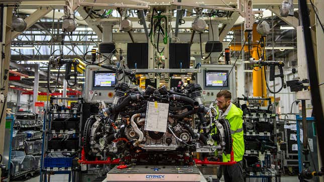 A photo of a car engine being assembled in a factory. 