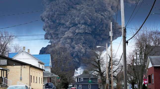 A black plume rises behind a home in East Palestine on Feb. 6, 2023.