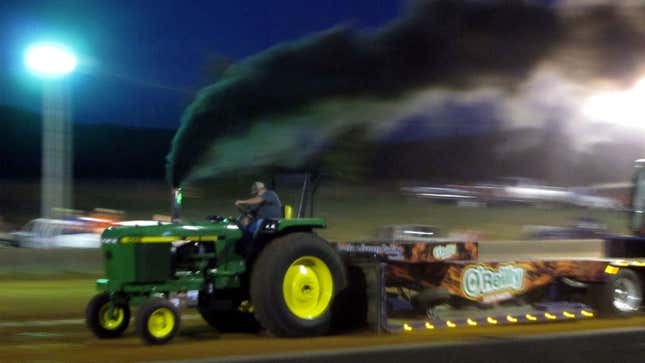 A photo of a tractor with plumes of smoke coming from its exhausts. 