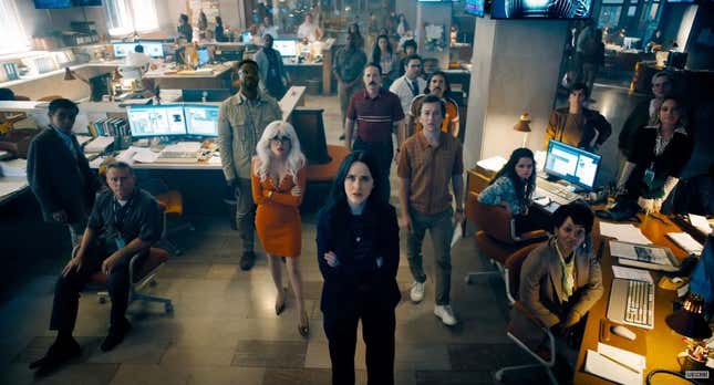 Lois Lane and the Daily Planet team stand looking up at what's presumably a TV screen.