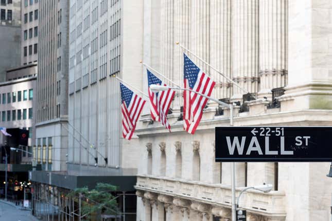 Wall Street sign with American flags and New York Stock Exchange in New York City