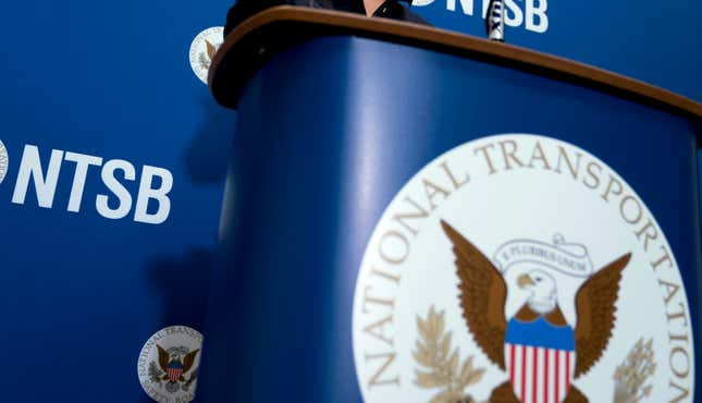 FILE - The National Transportation Safety Board logo and signage are seen at a news conference at NTSB headquarters, Dec. 18, 2017, in Washington. A broken pin might have caused a landing gear failure that left an Alaska Airlines jet resting on one of its engines last month. The National Transportation Safety Board said in a preliminary report Monday, Sept. 11, 2023, that after the pin broke, the landing gear punched through the top of the left wing. (AP Photo/Andrew Harnik, File)