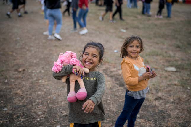 A little girl laughs clutching a doll at a fair in Hagioaica, Romania, Saturday, Sept. 16, 2023. For many families in poorer areas of the country, Romania&#39;s autumn fairs, like the Titu Fair, are one of the very few still affordable entertainment events of the year. (AP Photo/Vadim Ghirda)