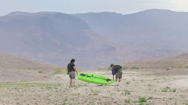 People carry a boat over dry ground at Lake Mead, which is drying up due to overuse and drought.