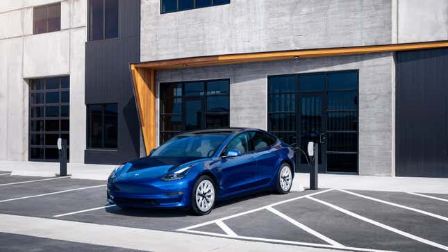 Ein blaues Tesla model 3, das vor einem Gebäude auflädt