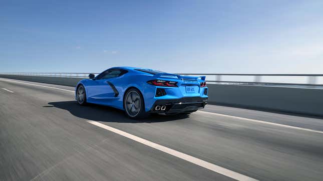 A bright blue C8 Corvette Stingray driving on a bridge