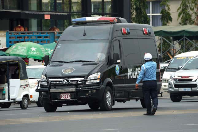 FILE - A Cambodian police man directs traffic as a convoy of police vehicles that was reportedly carrying Japanese citizens who were taken into custody on suspicion of running phone scams moves along a street on their way to Phnom Penh International Airport in Phnom Penh, Cambodia, on April 11, 2023. Twenty-five Japanese nationals suspected of involvement in an online scam operation based in Cambodia were deported to Japan on Wednesday, Nov. 8, said Gen. Khieu Sopheak, a spokesperson for Cambodia&#39;s Interior Ministry. (AP Photo/Heng Sinith, File)