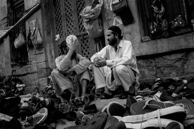 Two shoe sellers await customers on the sidewalk they have made their home.